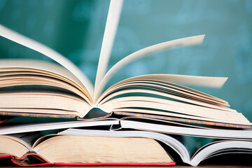 Naklejka premium A stack of books opened in front of the blackboard