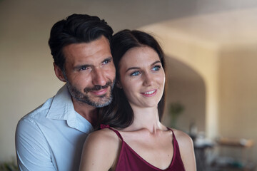 Fototapeta premium Authentic shot of happy lovely smiling married elegantly dressed couple is enjoying time together and embracing as sign of timeless love at home before going out for romantic dinner at night.