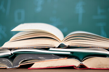 A stack of books opened in front of the blackboard