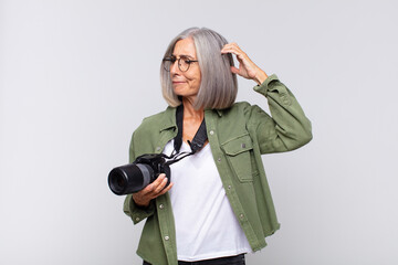 middle age woman feeling puzzled and confused, scratching head and looking to the side....