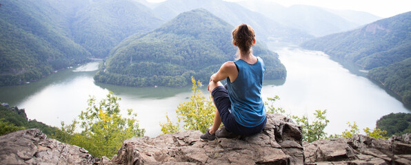 woman and dog on mountain top above lake