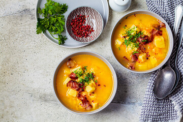 Pea soup with bacon and parsley in gray bowls, gray background, top view.