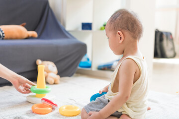 Obraz na płótnie Canvas A 1.5-year-old baby boy plays with educational toys on the carpet