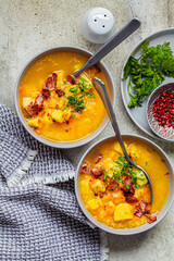 Pea soup with bacon and parsley in gray bowls, gray background, top view.