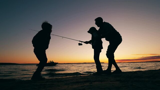 Father is teaching his happy kids to catch fish
