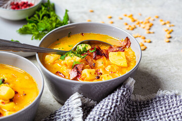 Pea soup with bacon and parsley in gray bowls, gray background.