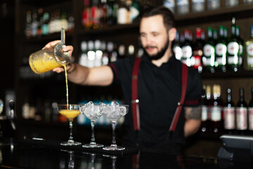 Bartender making refreshing coctail on a bar background. Dark moody style. Ice in the glass. Fosuc on glass