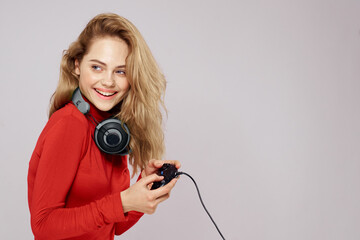 Woman with headphones controller in hands a console game fun leisure red jacket lifestyle light background