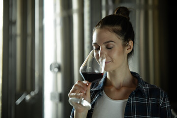 Authentic shot of happy successful female winemaker is tasting a flavor and checking red wine...