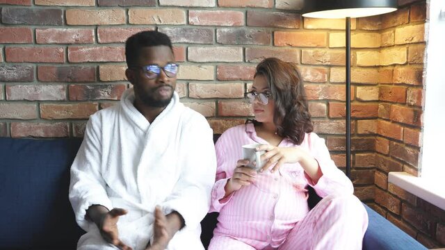 Beautiful pregnant woman and black man discuss plans for future, want to be a good parents for baby, discuss all purchases they need.