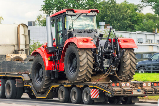 Powerful red tractor on a platform trailer road transportation.