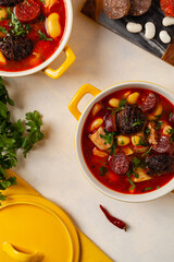 Traditional Spanish goulash soup. Fabada Asturiana. Served with a yellow clay pot with lid. Top...