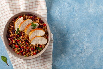 Trendy lunch with cereal, beetroot and chicken. Served in a bowl on a blue painted background. Top view.
