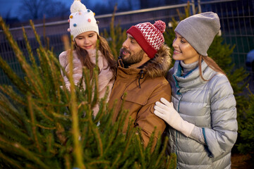 family, winter holidays and people concept - happy mother, father and little daughter choosing...