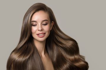 portrait of beautiful smiling brunette woman with wavy hair. Woman with hairstyle and makeup on gray background