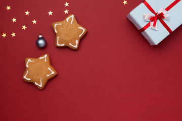 Cookies in the shape of stars and a gift in a box on a red background. Flat lay, top view, copy space. Christmas New Year composition