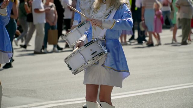 Street performance of festive march of drummers girls in blue costumes on city street. Majorettes in the parade