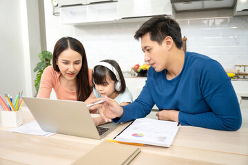 Asian father, mother and daughter doing home work togather in living room, education at home and family concept