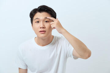 Young attractive man checking his skin and touching wrinkles on his face