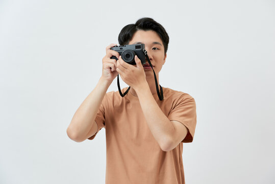 Young Asian man taking photo with his camera when he travelling over white background.