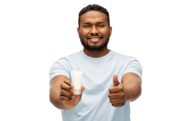 grooming, skin care and people concept - happy smiling african american with moisturizer showing thumbs up over white background