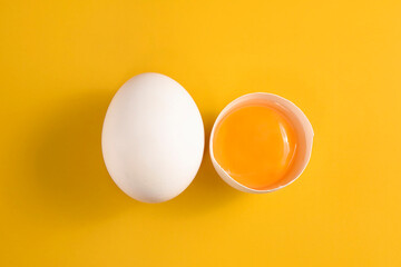 Whole egg and yolk on the yellow background