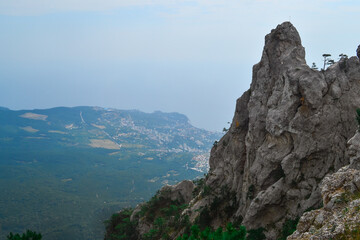 large steep sharp stone rock Ai-petri cliff against the background of Black sea coastline in Crimea, the city below, summer