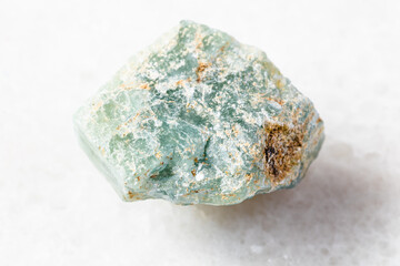 closeup of sample of natural mineral from geological collection - rough Apatite rock on white marble background