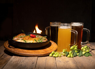 Bavarian sausages and three glasses of fresh beer. Hop branch lie on the table.