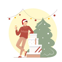 A cute funny young man in the sweater and Santa hat with wineglass celebrating Christmas. A guy near boxes of gifts under garland. A boy with drink near christmas tree.