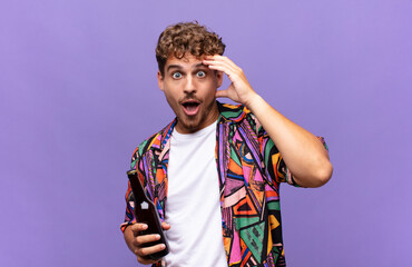 young man looking happy, astonished and surprised, smiling and realizing amazing and incredible...