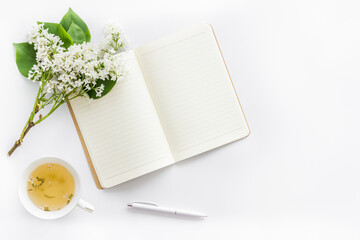 Jasmine flowers bouquet with cup tea and notepad top view