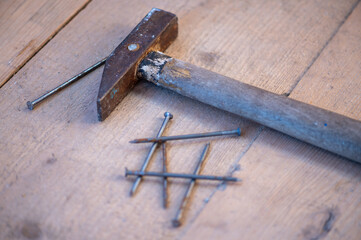 Old vintage hammer and nails on a wooden background, close-up, selective focus.