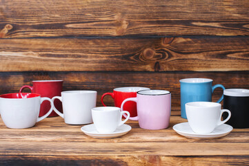 multicolored cups on a dark wood texture background.