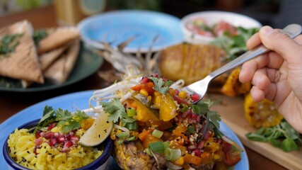 Fork picking thai curry served in a pineapple. Healthy oriental plant-based cuisine 
