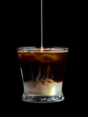 Cafe bombon tipico de españa sobre fondo negro con leche condensada