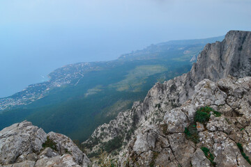 Fototapeta na wymiar Abyss in steep rocks Ai-Petri, Crimea. Cliff against the backdrop of blue coastline with city and forest, beautiful summer landscape