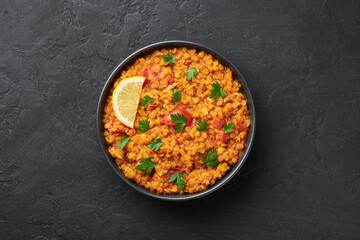 Red lentils dal in black bowl on dark slate table top. Lentils tomato dhal is indian cuisine dish...