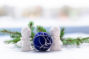 Fir tree branches and white crocheted angels on light background with bokeh. Christmas hamdmade gift concept.