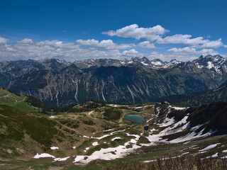 Beautiful panorama view near the top of alpine Fellhorn peak (2,037 m), Oberstdorf, Allgäu, Bavaria, Germany with mountain station of Fellhornbahn and turquoise shimmering Schlappolt Lake.