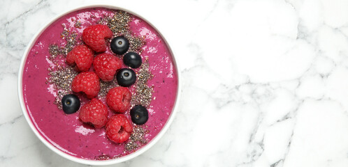 Delicious acai smoothie with raspberries and chia seeds on white marble table, top view. Space for text