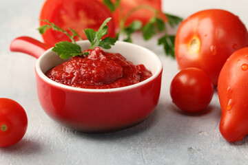 Tomato paste in a red gravy boat and ripe, juicy tomatoes. Ingredients for many dishes.