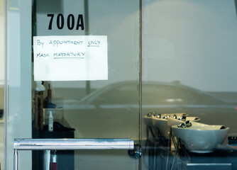 Hair salon in miami has sign on door requiring mask and appointment due to pandemic 