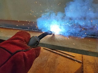 A welder is welding under flux, a type of electrical procedure.  Welding takes place by arc heating between the bare electrodes and the work piece metal.  The welding electrodes are fed continuously b - Powered by Adobe