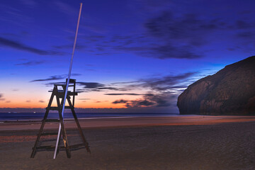 sunrise on the beach with the lifeguard's chair and the Neowise comet in the background in the sky
