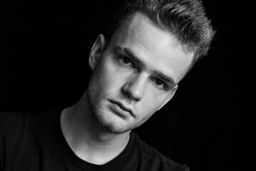 Portrait of a serious, pensive young unshaven guy, black and white photo
