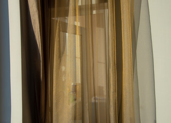 Abstract background. A gold curtain hanging from a window against the wall.