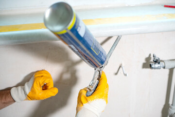 Worker using a polyurethane foam to fix the window sill and close the holes.