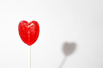red heart shaped lollipop on white background