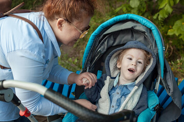 Mother and disabled son walk in the fresh air in a chair, medical mobile equipment